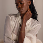 Model wearing the gold Heart Carabiner Paperclip Bracelet styled with sheer, pleated blouse.