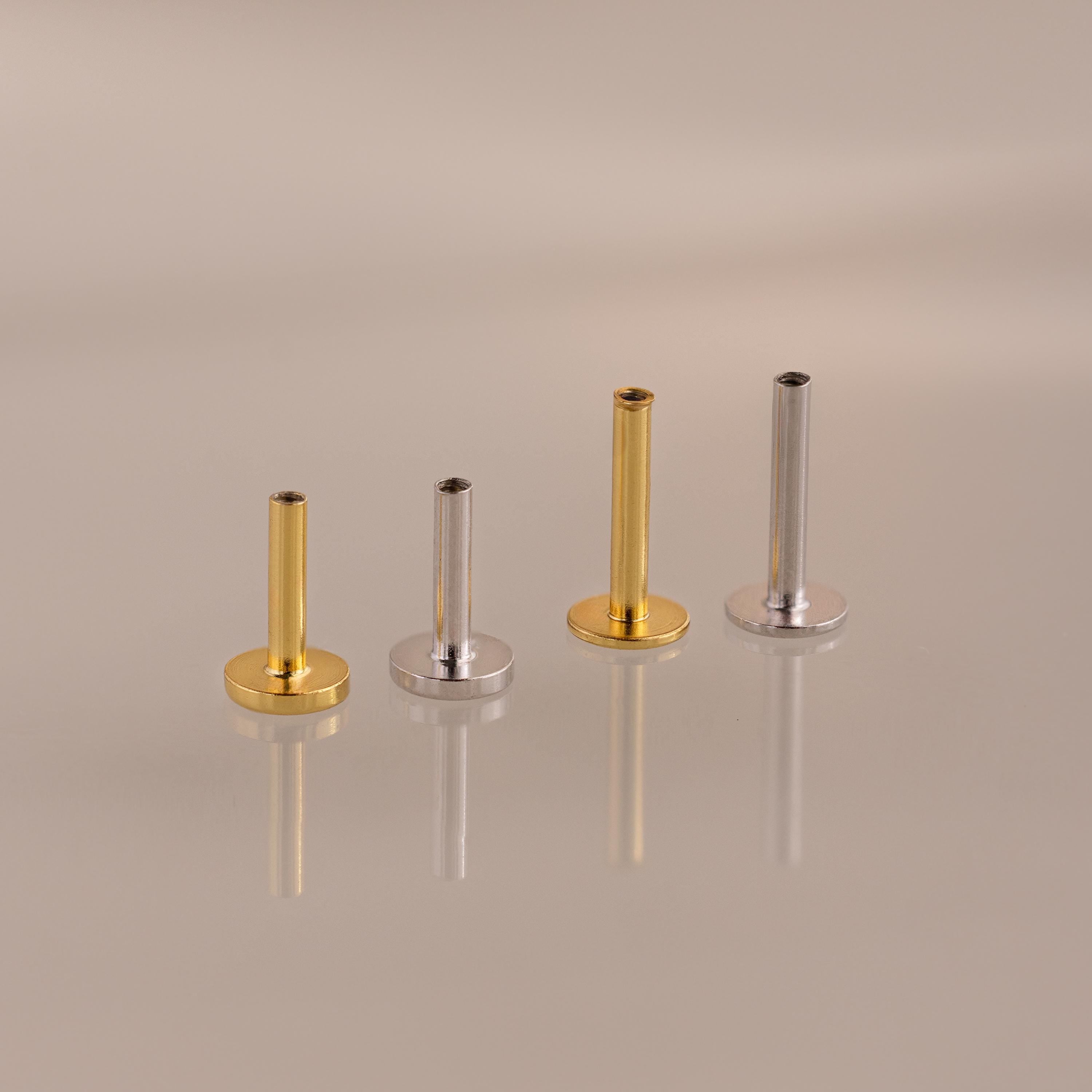 The Flatback Post Set features two gold and two silver posts arranged in a row on a reflective surface, highlighting their sleek design ideal for everyday ear jewelry.