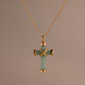 Gold chain necklace featuring a green jade cross pendant with polished gold end caps and a gold X-shaped accent at the center.