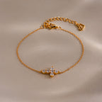 Gold chain bracelet with an adjustable clasp, featuring a cross shaped charm set with small round white gemstones.