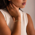 Woman wearing a sleeveless knit top and the Leaf Link Bracelet, with her hand touching her neck.