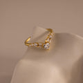 Gold heart curve cluster diamond ring featuring a central heart shaped stone with a row of round and marquise diamonds set in a V shaped band.