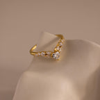 Gold heart curve cluster diamond ring featuring a central heart shaped stone with a row of round and marquise diamonds set in a V shaped band.