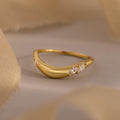 The Organic Diamond Curve Ring features a gold band with three sparkling marquise diamonds set on one side, showcased against a neutral background.