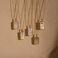 Five elegant gold chain necklaces with rectangular pendants, each adorned with engraved designs, small colored gems, and pearls—a stylish Pearl Zodiac Birthstone Necklace perfect for personalized jewelry lovers.