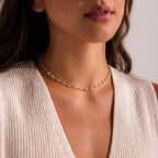 Gold pearl chain choker necklace with white pearls set in oval gold links, shown on model for a modern and elegant look.