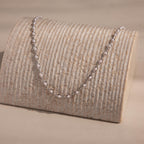 Silver pearl chain necklace with white pearls set in oval silver links, displayed on textured stand for an elegant, modern presentation.