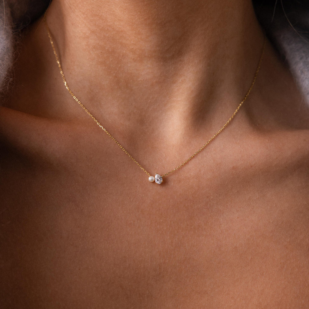 The Teardrop Garnet & Pearl Necklace features a delicate pearl strand with a garnet teardrop pendant, resting elegantly on the collarbone—an ideal milestone gift.