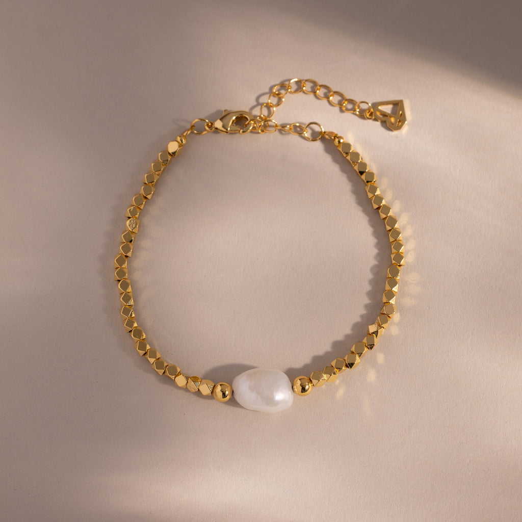 Beaded Pearl Bracelet in gold featuring faceted metallic beads with a single natural white pearl centerpiece, displayed on a neutral background with delicate lighting for an elegant presentation.