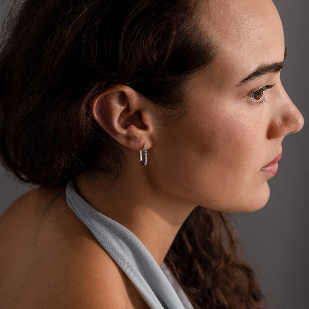 Woman with long brown hair shown in profile, wearing Dainty Pave Link Earrings in Sterling Silver and a light gray halter top.