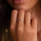 A hand near the lips showcases the Woven Multiple Birthstone Ring in Sterling Silver, a vintage-inspired jewelry piece adorned with colorful gemstones.