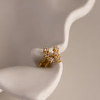 Pink Tourmaline Cluster Flatback Studs featuring small pink and clear gemstones, reminiscent of birthstone earrings, displayed on a smooth, wavy white surface.