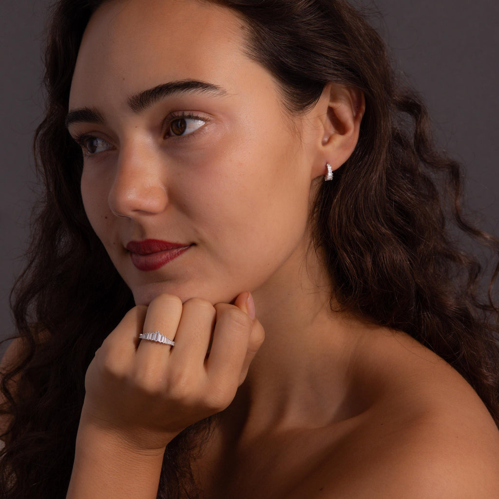 A woman with wavy hair exudes vintage glamour, resting her chin on her hand while wearing the Art Deco Diamond Earrings & Ring Set.