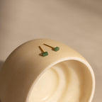 The Jade Bar Jewelry Set in 18K Gold features two gold stud earrings with green rectangular stones, displayed on a smooth off-white ceramic surface.