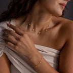 Woman wearing the Heart Station Necklace & Bracelet Set, styled with an off-shoulder white top.