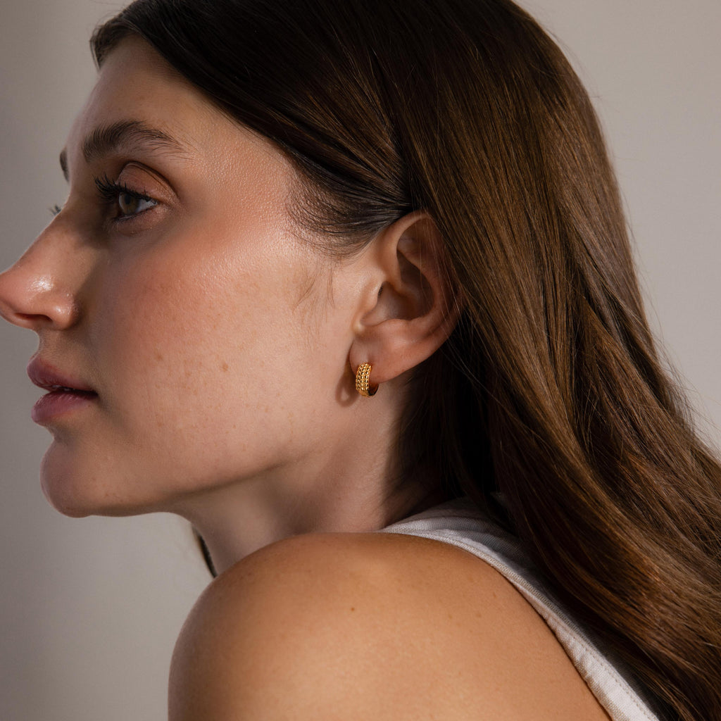 Woman with long brown hair is shown in profile wearing Beaded Chunky Hoops against a neutral background.