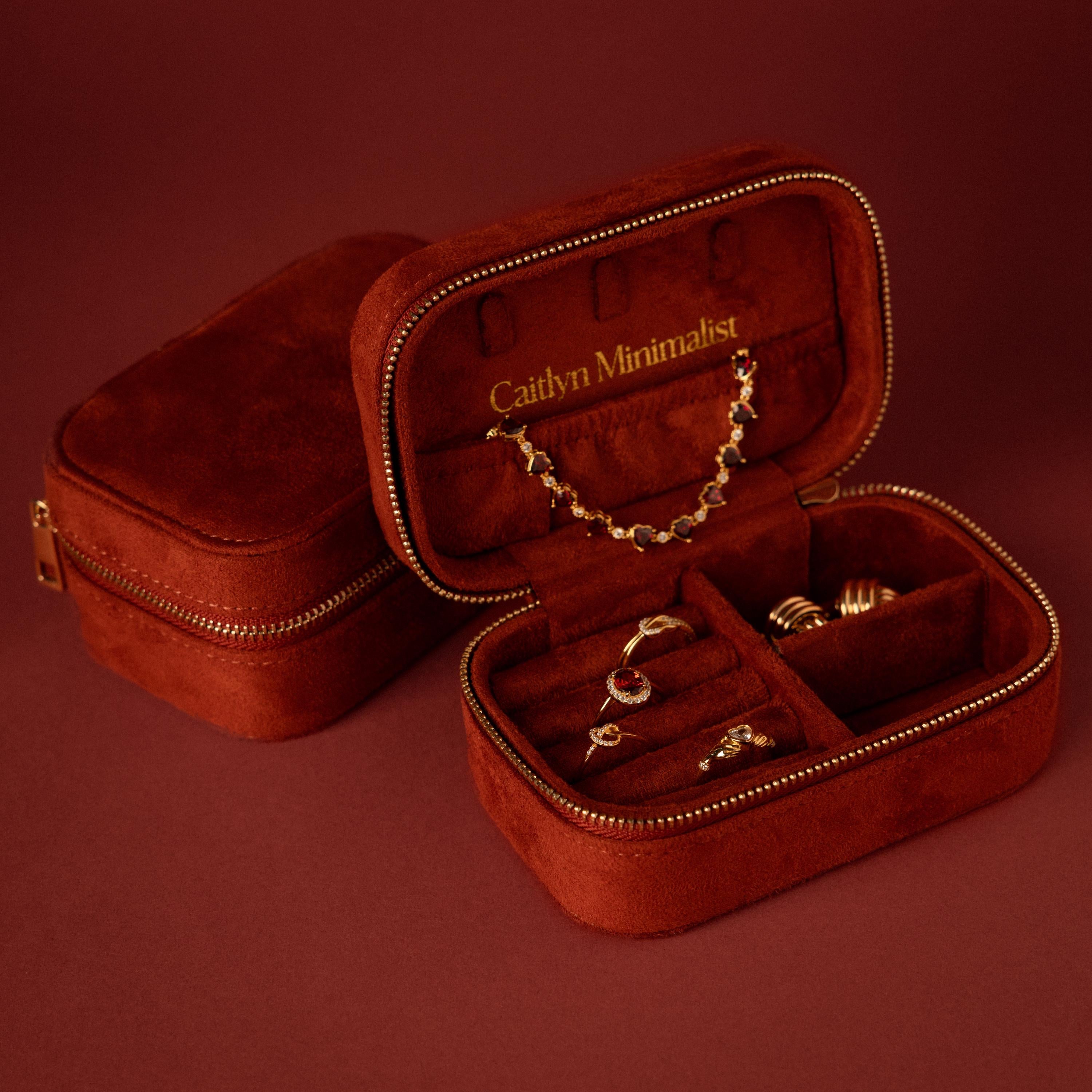 Open cherry red velvet jewelry case with gold rings, earrings, and necklace, labeled Caitlyn Minimalist—a perfect luxury jewelry storage solution.