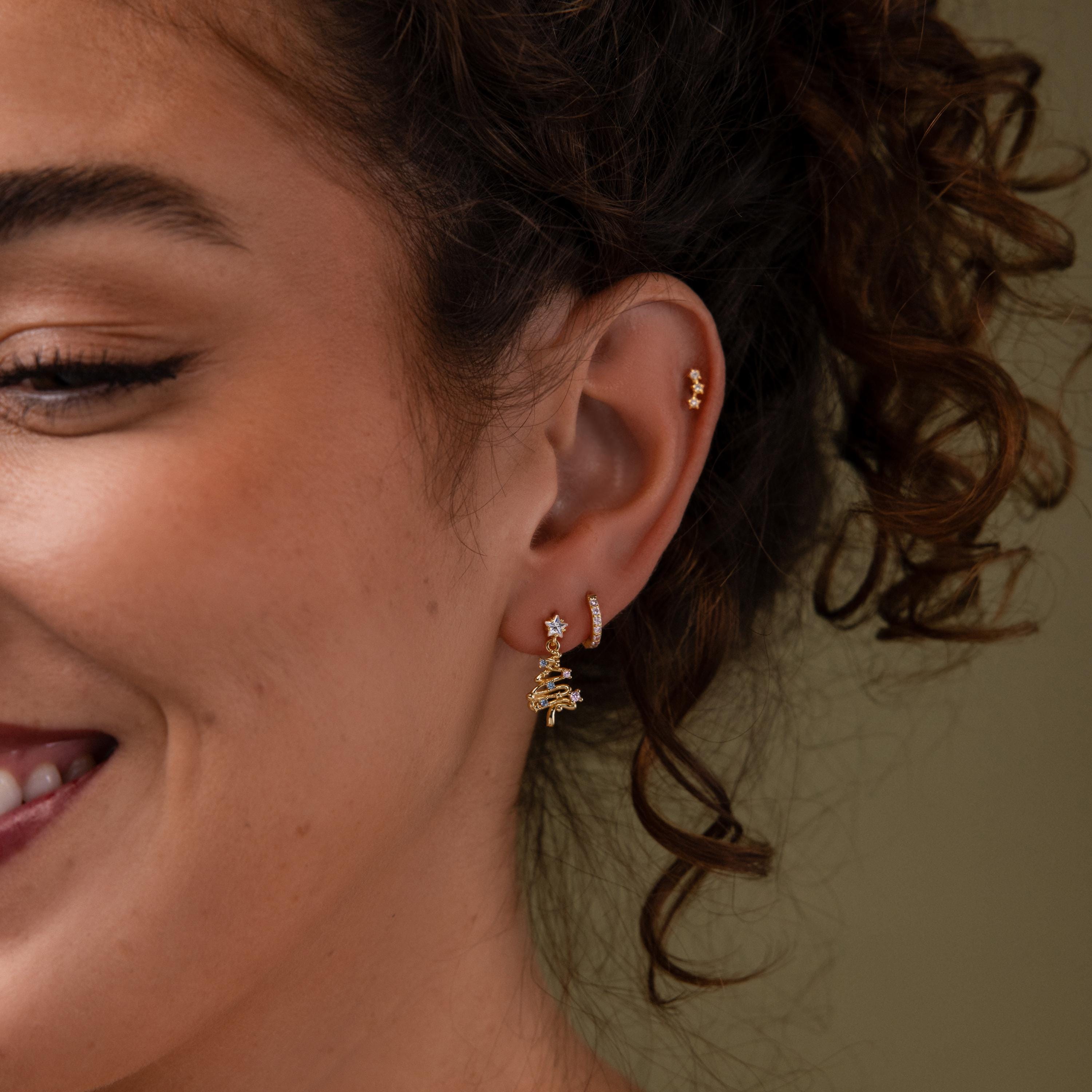 Model wearing our Holiday Diamond Tree Studs in Gold, styled with our Coco Huggies and Celestial Star Studs