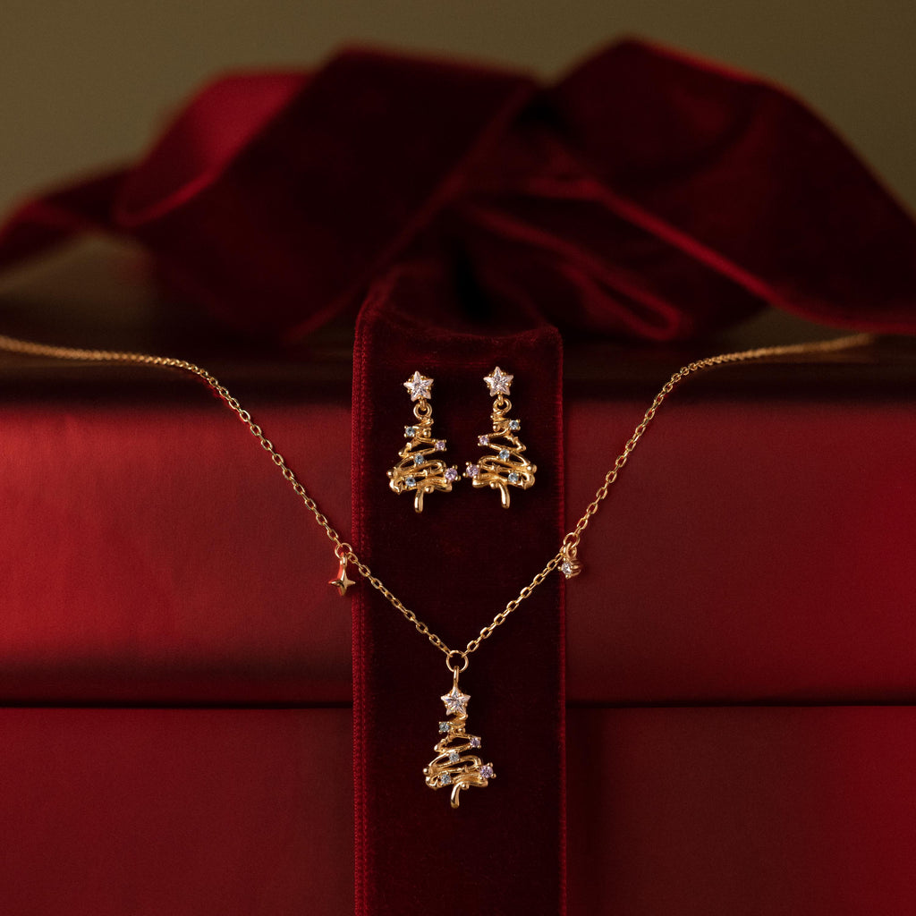Flatlay of a Christmas tree earring and neckalce jewelry set against a red gift box