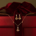 Flatlay of a Christmas tree earring and neckalce jewelry set against a red gift box