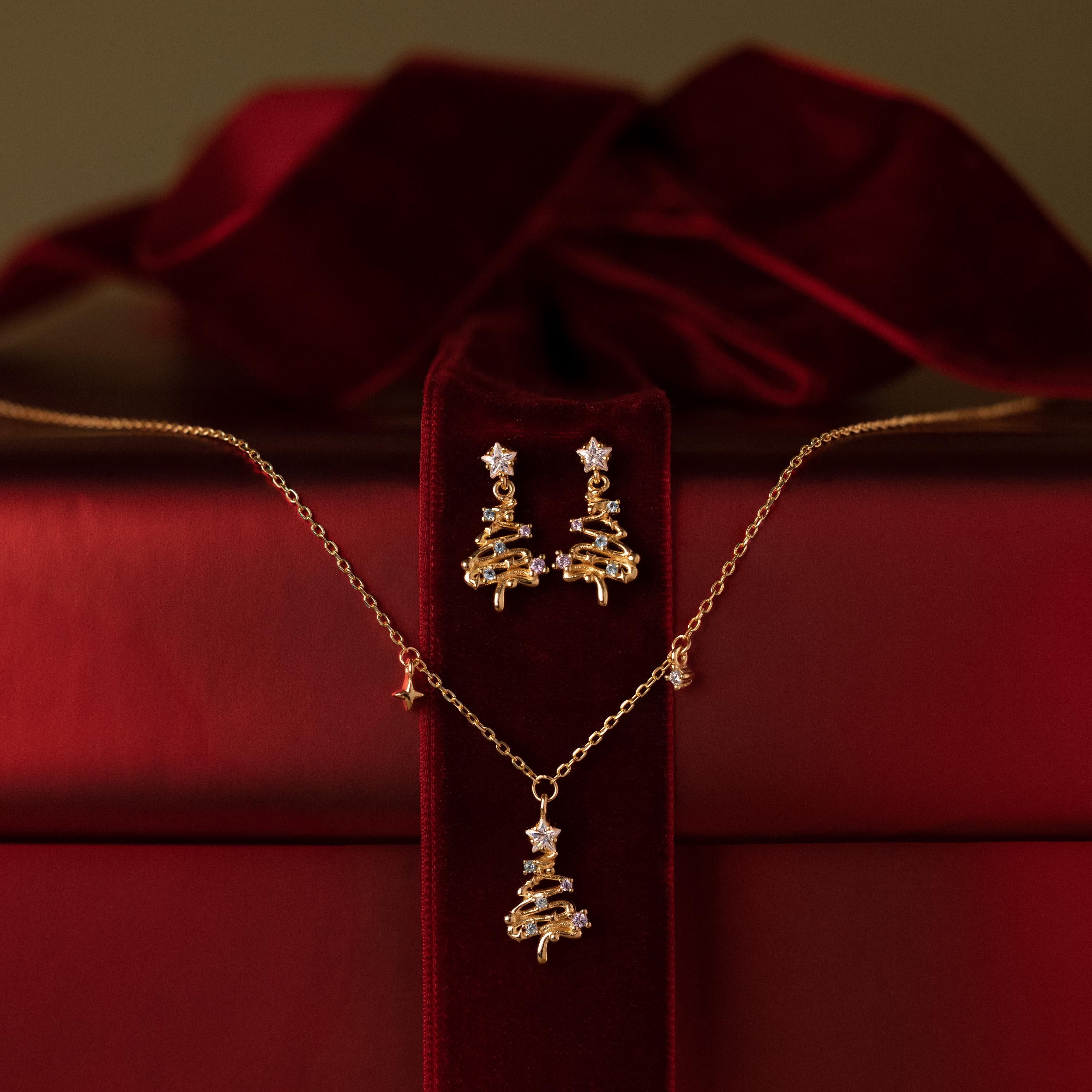 Flatlay of a Christmas tree earring and neckalce jewelry set against a red gift box