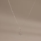 Flat;ay of our Diamond Poinsettia Necklace in Silver on a beige background