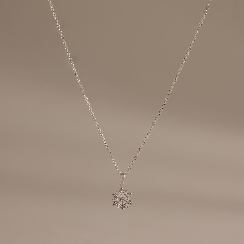 Flatlay of our Diamond Poinsetta Pendant Necklace in Silver