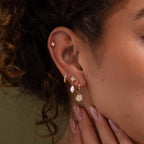 Model wearing our Diamond Poinsettia Hoops, styled with our Daydreamer Diamond studs, Coco Pave Huggies and Moon and Star Stud Earrings