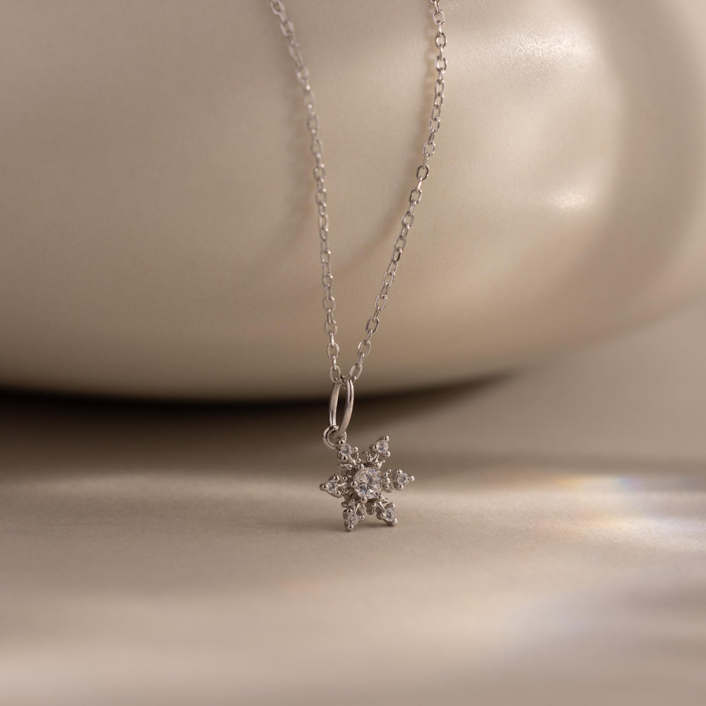 Flatlay of our Diamond Snowflake Necklace against a white bakground