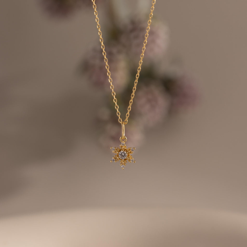 Flatlay of our Diamond Snowflake Necklace in Gold finish