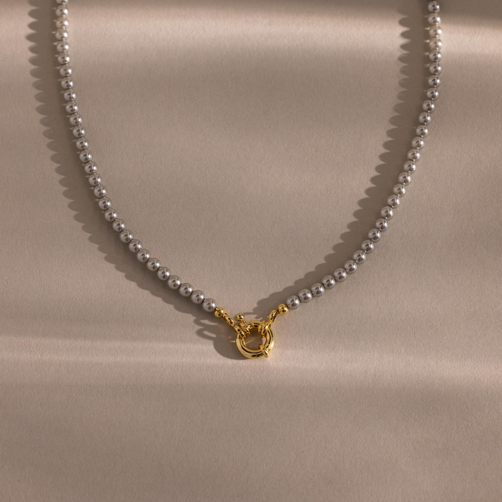 Flatlay of our Smoky Pearl Clasp Necklace on a beige background