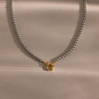 Flatlay of our Smoky Pearl Clasp Necklace on a beige background