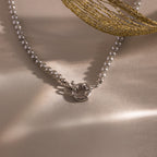 Flatlay of our Smoky Pearl Clasp Necklace on a beige background
