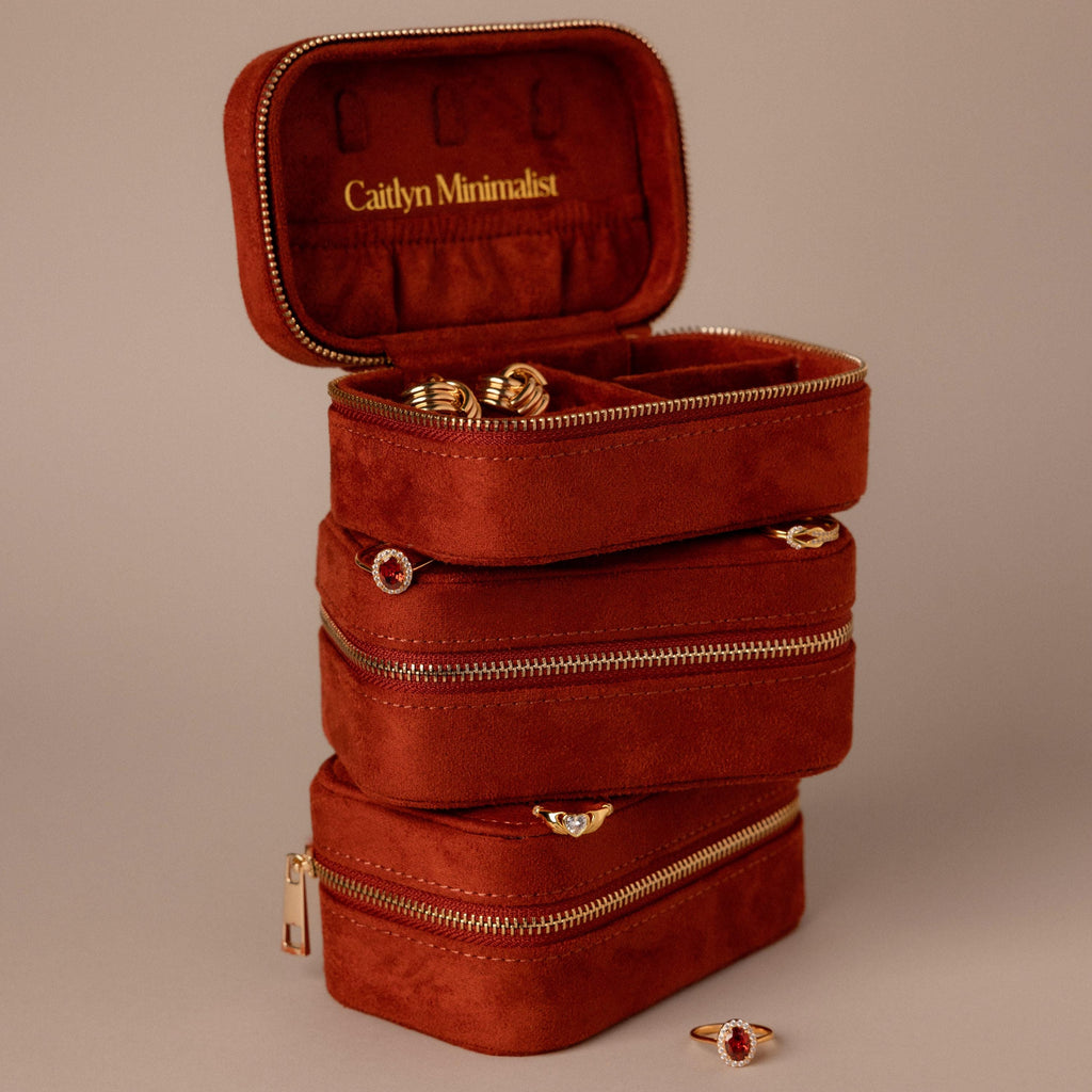 The Cherry Red Velvet Jewelry Case features gold zippers; one is open, revealing organized rings and earrings—an ideal luxury storage solution for your jewelry.