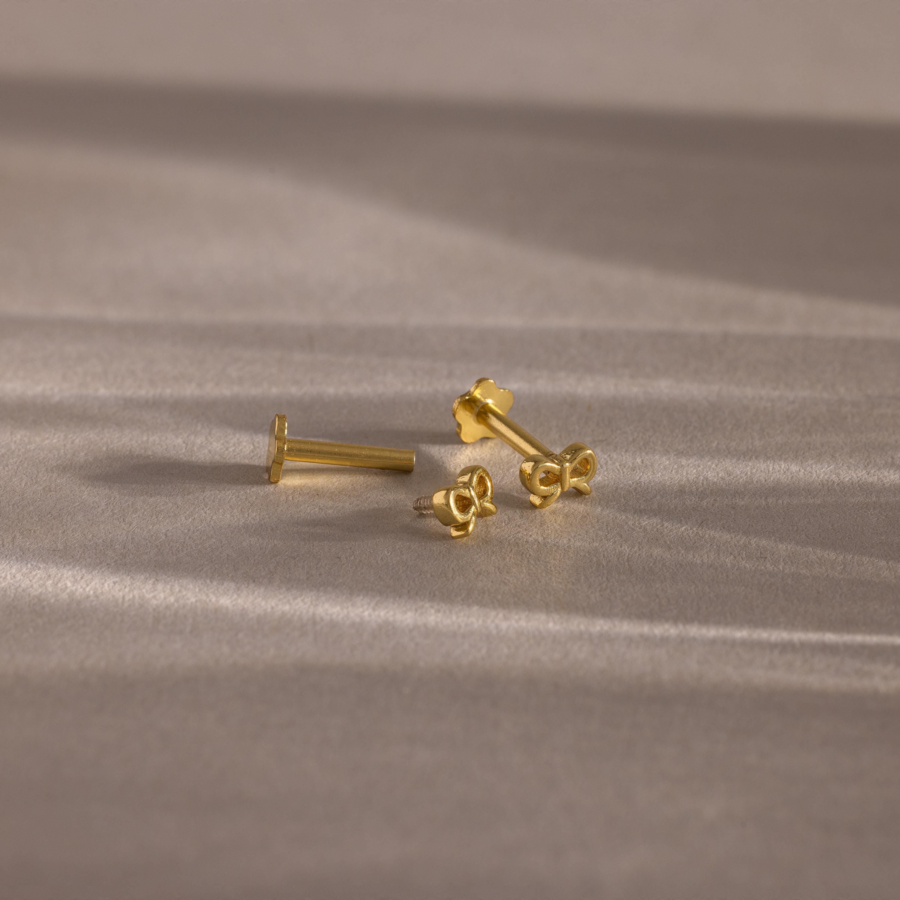 Flatlay showing our Tiny Bow Flatback Studs in 18K Gold with the flatback posts separated