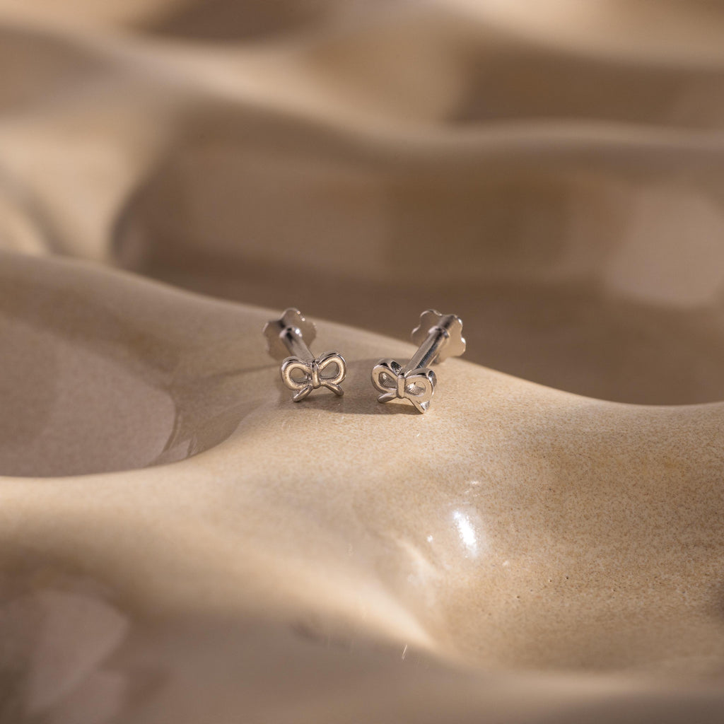 Close up flatlay of our Tiny Bow Flatback Studs in Sterling Silver