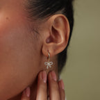 Close up of model wearing our Pave Bow Charm Hoops in Gold