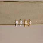 Flatlay of 2 pairs of our Hammered Diamond Teardrop Hoops in Silver and Gold