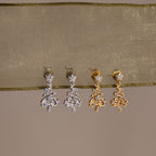 Pair of silver and gold earrings on a beige fabric background