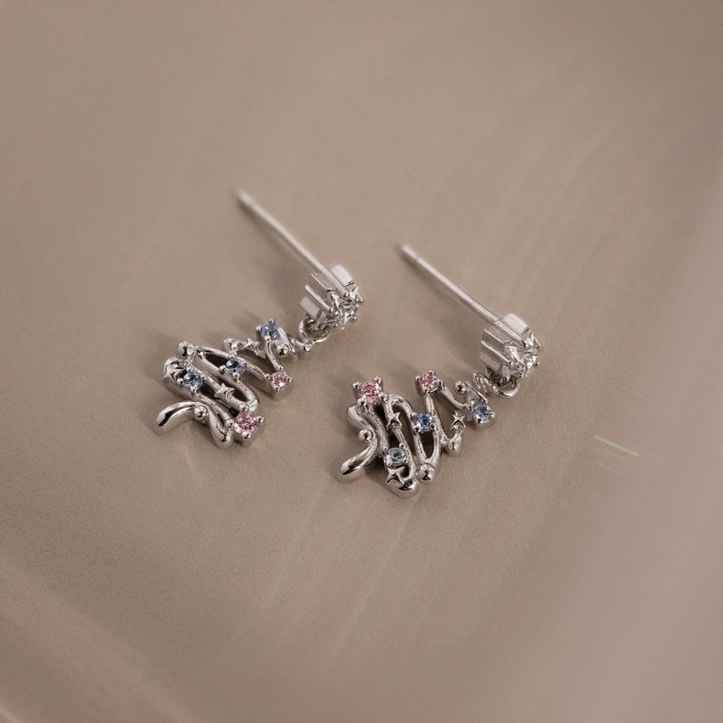 Flatlay of our Holiday Tree Studs in silver with gemstones on a beige surface