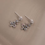 Flatlay of our Holiday Tree Studs in silver with gemstones on a beige surface