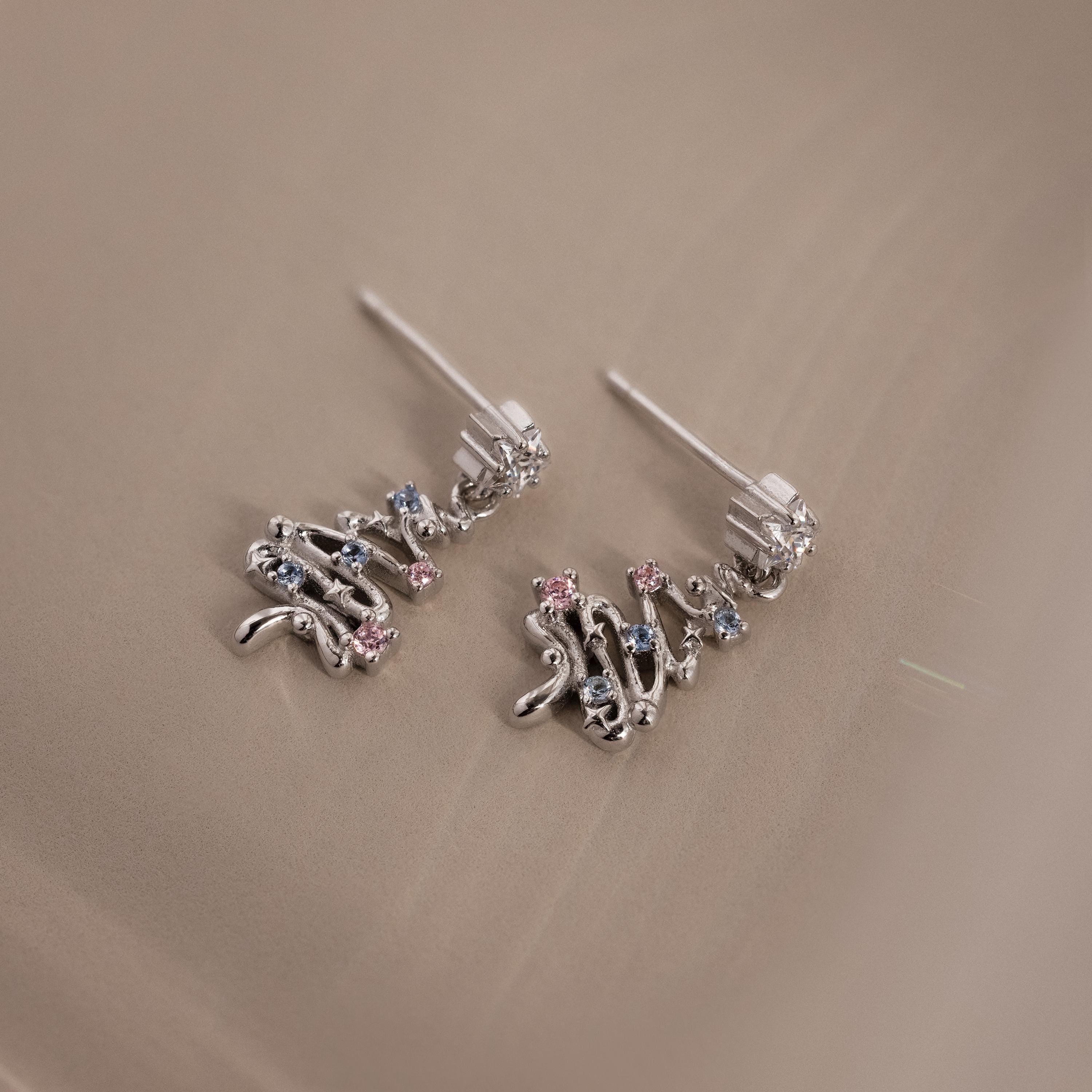 Flatlay of our Holiday Tree Studs in silver with gemstones on a beige surface