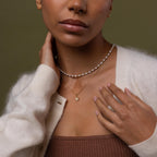 Woman wearing our Diamond Poinsetta Pendant Necklace in gold paired with a pearl necklace