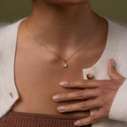 Model wearing our Diamond Poinsetta Pendant Necklace, hand resting on chest.