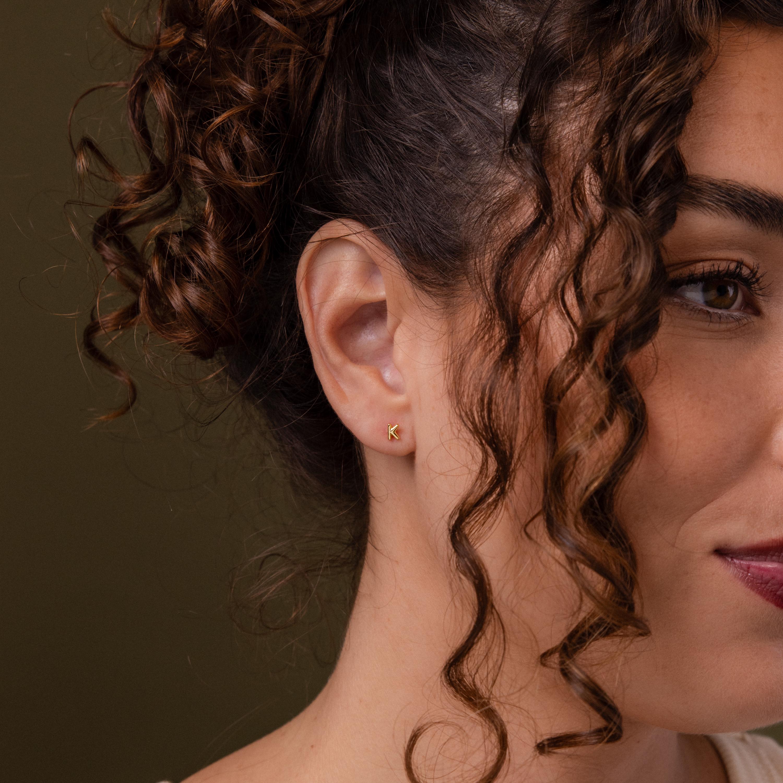 Close-up of a model wearing our Bubble Initial Flatback Studs in Gold