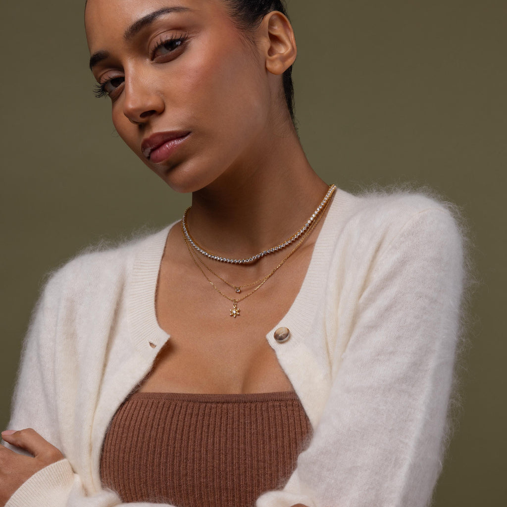 Faraway shot of a model wearing our Diamond Snowflake Necklace, styled with our Diamond Tennis Choker Necklace and Dainty Diamond Necklace
