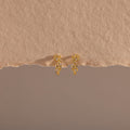 Photo of our Diamond Leaf Hoops in 18K Gold on a beige background
