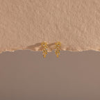 Photo of our Diamond Leaf Hoops in 18K Gold on a beige background