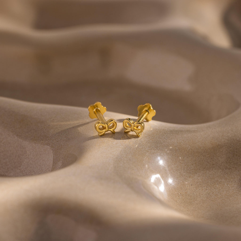 Flatlay of our Tiny Bow Flatback Studs in 18K Gold