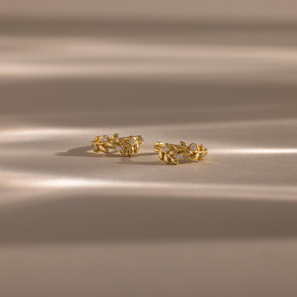 Close up flatlay image of our Diamond Leaf Hoops in 18K Gold